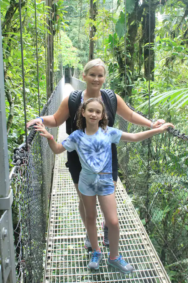 Tour group enjoying the majestic panoramic views of the Arenal Volcano from a suspension bridge