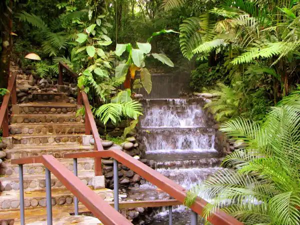 Soothing natural freshwater waterfall cascading into a crystal-clear thermal pool at Eco Termales sanctuary